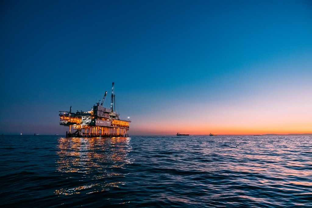 A striking image of an offshore oil rig at sunset off the coast.